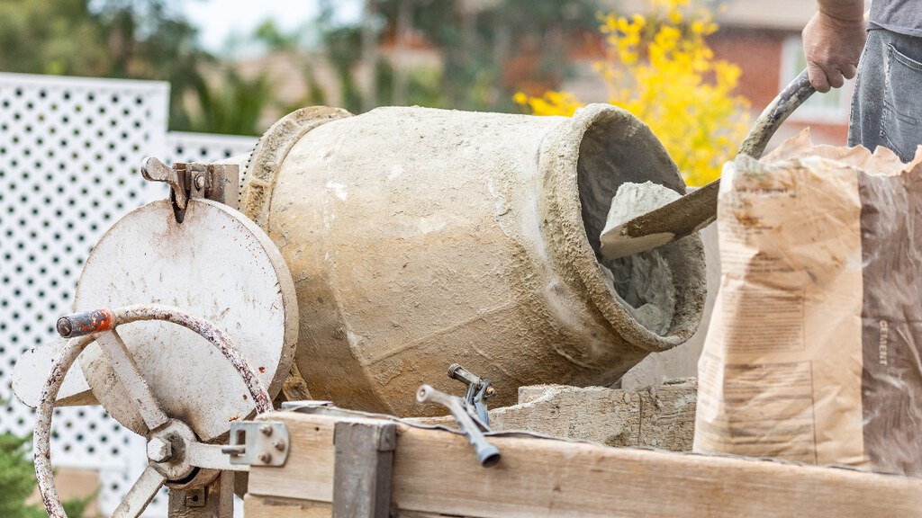 A worker mixing concrete on site in a cement mixer.