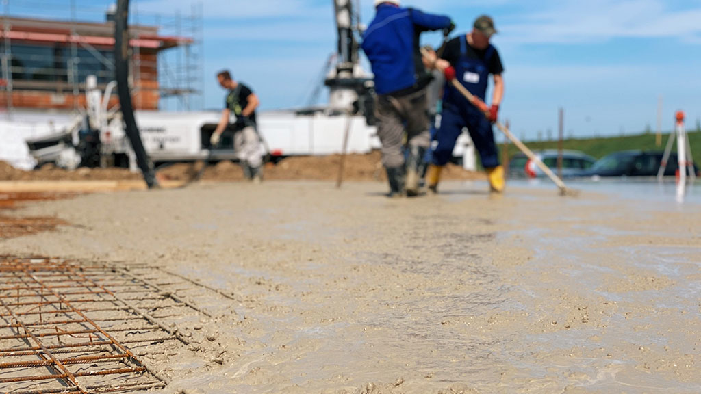 Concrete foundation being poured into formwork with visible steel reinforcement.