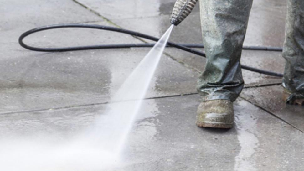 A pressure washer cleaning a concrete path