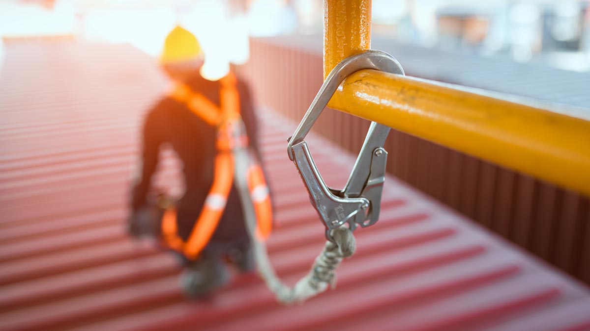Man wearing a safety harness that's is shackled to a railing