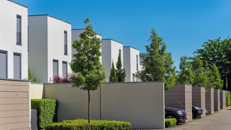 Modern white homes with concrete boundary walls and landscaped gardens