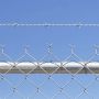 A close up of chain link fence topped with barbed wire