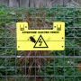 An electric fence with a yellow warning sign that reads "Attention! Electric Fence"