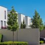 Modern white homes with concrete boundary walls and landscaped gardens