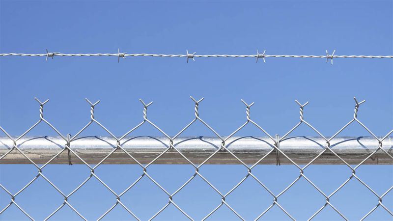 A close up of chain link fence topped with barbed wire