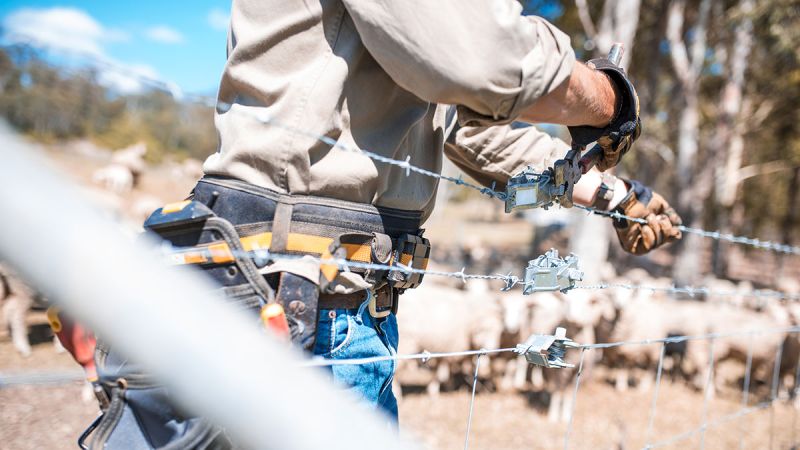 Man with tool belt constructing fence with joiner