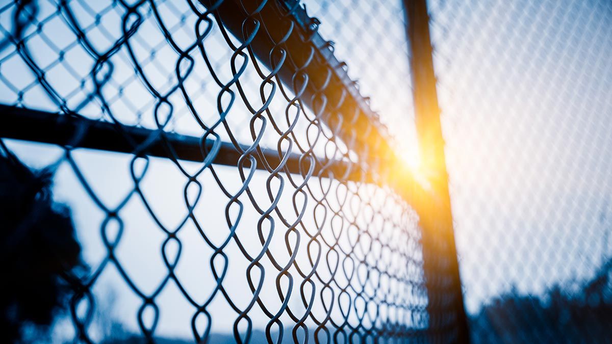 Galvanised chainlink fencing with sun in background