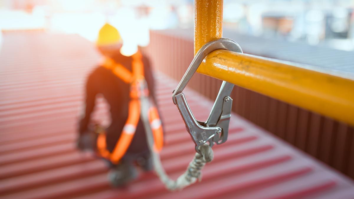 construction worker with safety harness attached to yellow pole