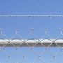 A close up of chain link fence topped with barbed wire