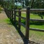 A wooden fence constructed from copper logs