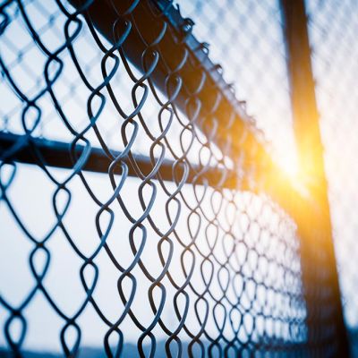 Galvanised chainlink fencing with sun in background